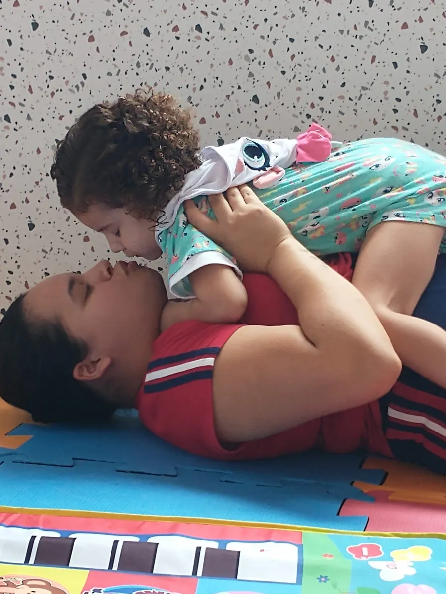Criança pequena no colo, deitada sobre o adulto, em contato próximo durante a sessão
