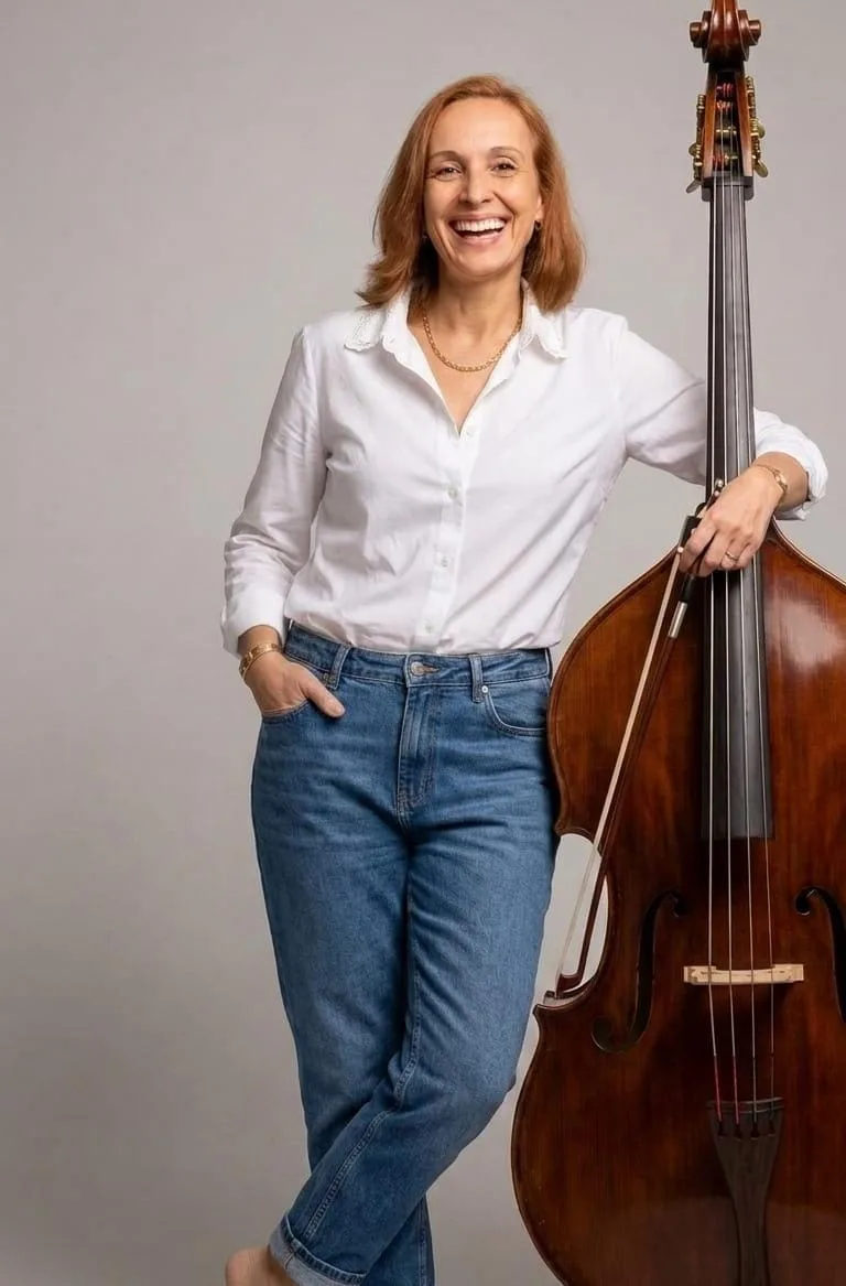 Cristiane Ruivo sorrindo, apoiada em seu contrabaixo