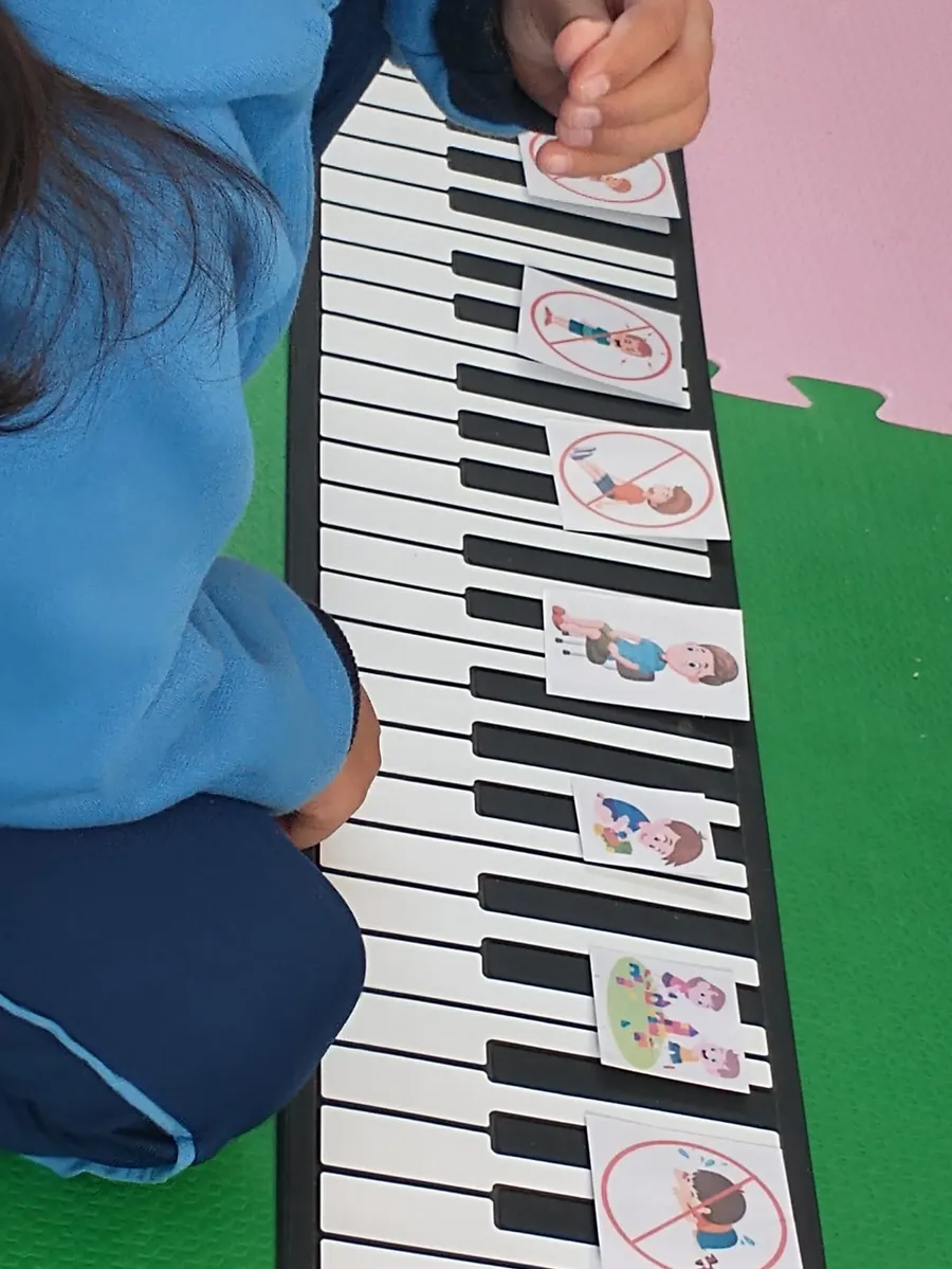 Criança organizando cartões de rotina sobre um teclado musical