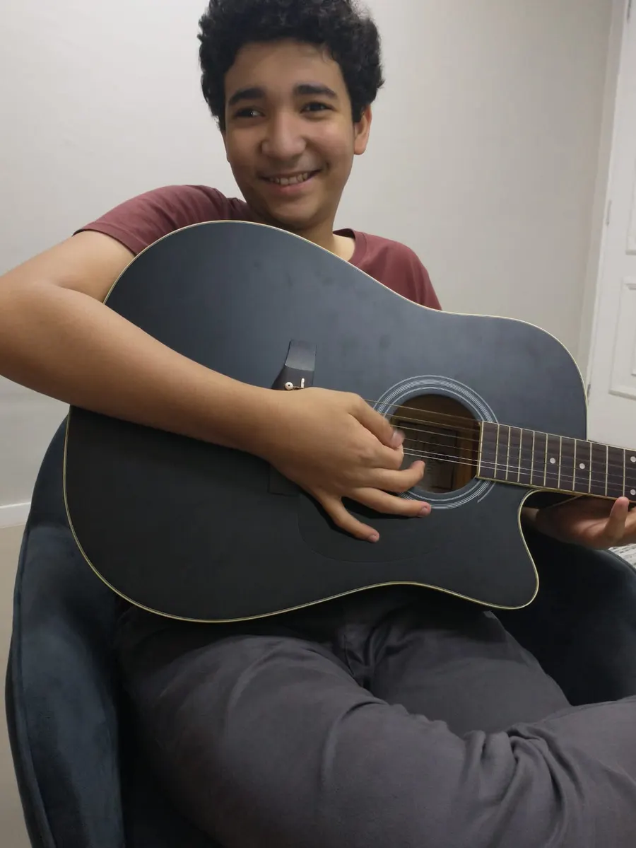 Adolescente sorrindo enquanto toca violão